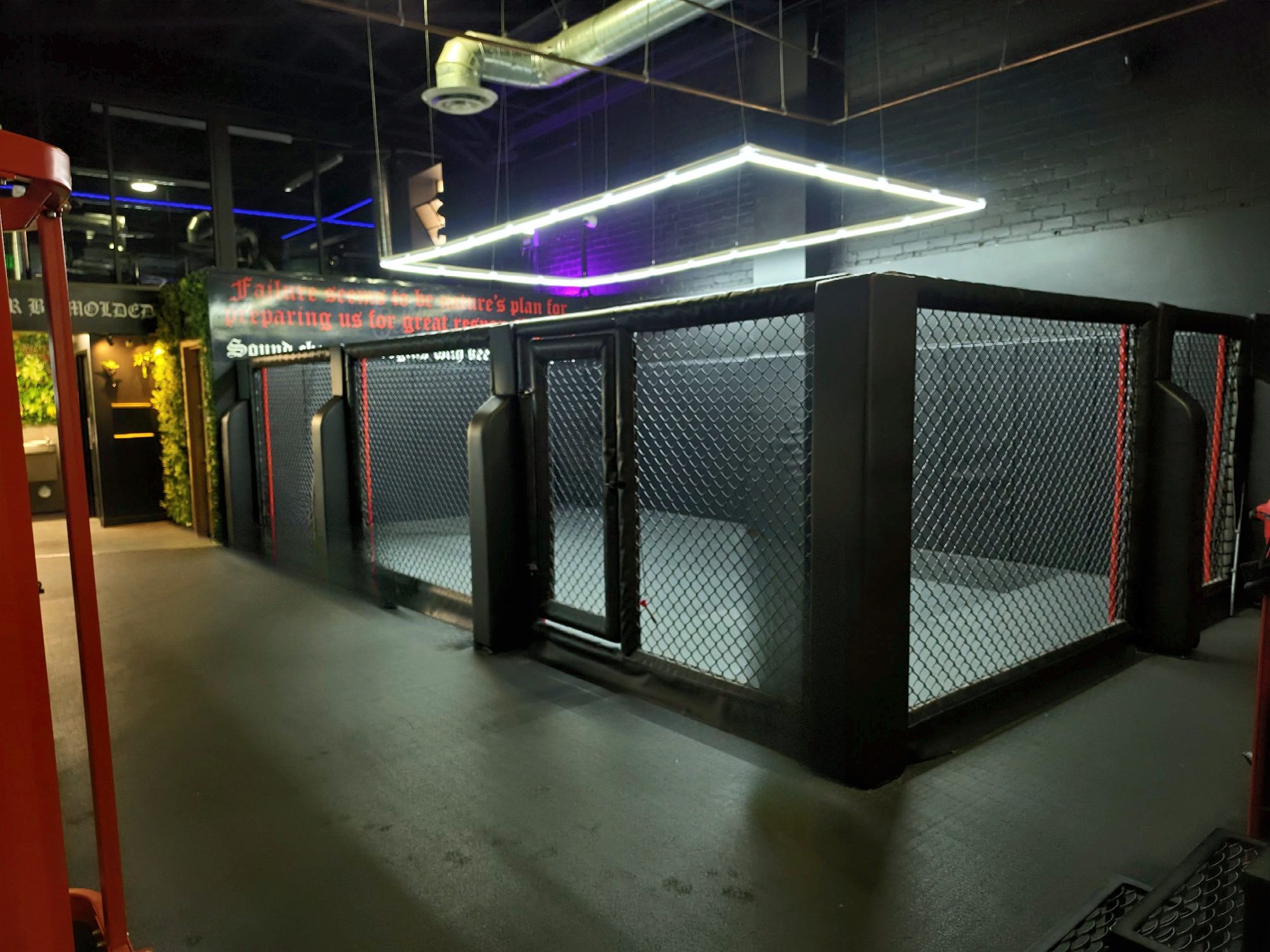The cage, lit from above, with a quote painted on the wall behind it