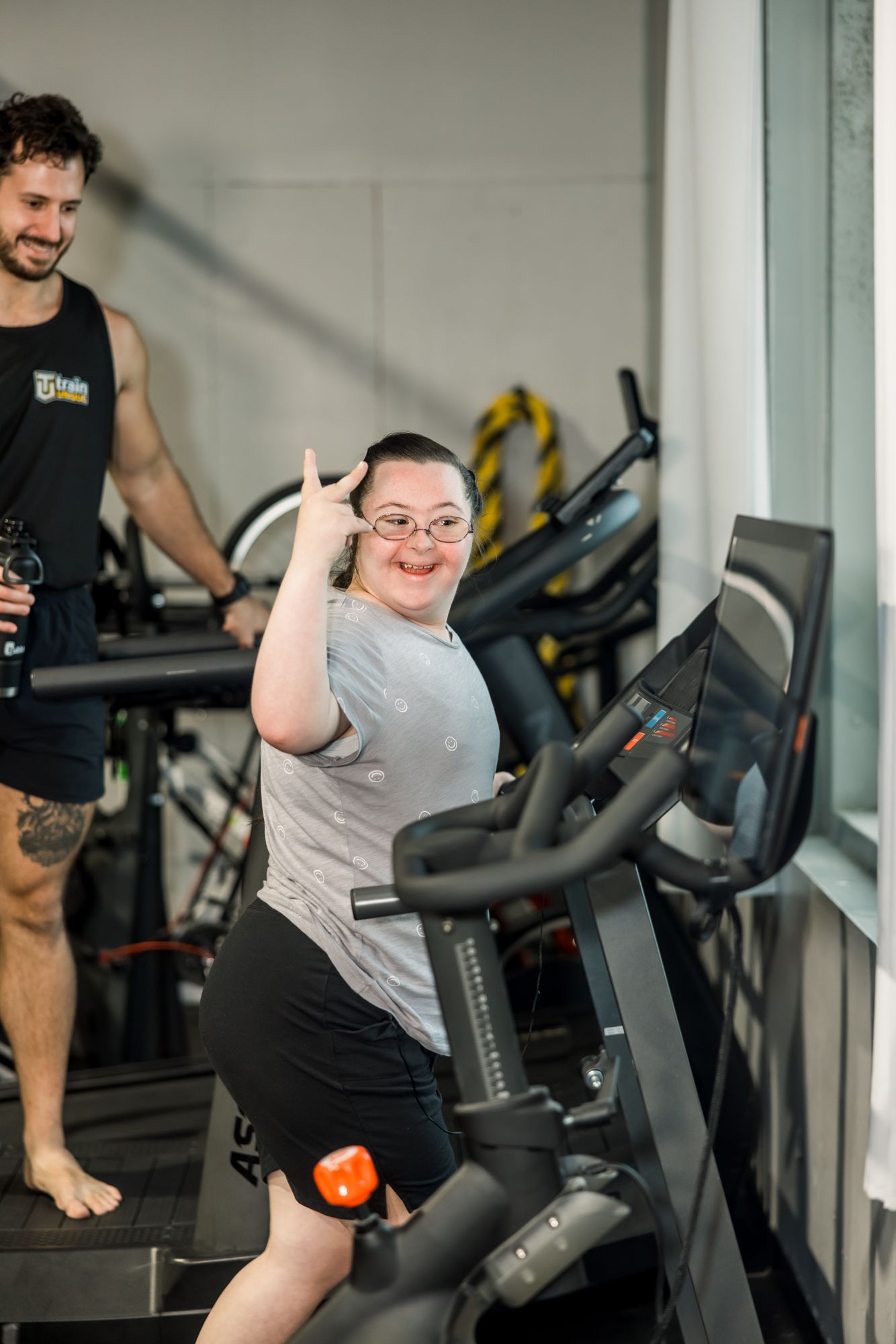 An athlete on the bike giving a thumbs-up, his coach grinning behind him