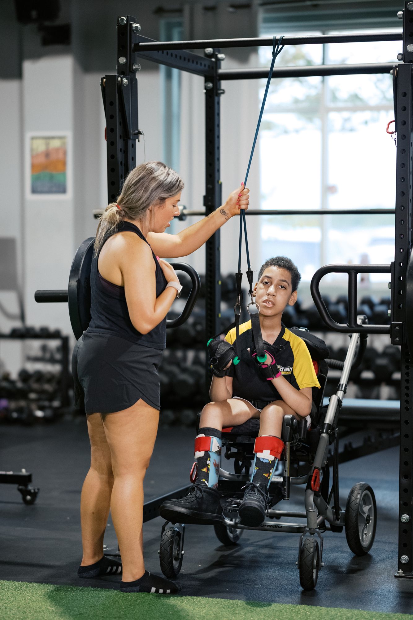 An athlete in his chair working the cable machine, his coach at the stack